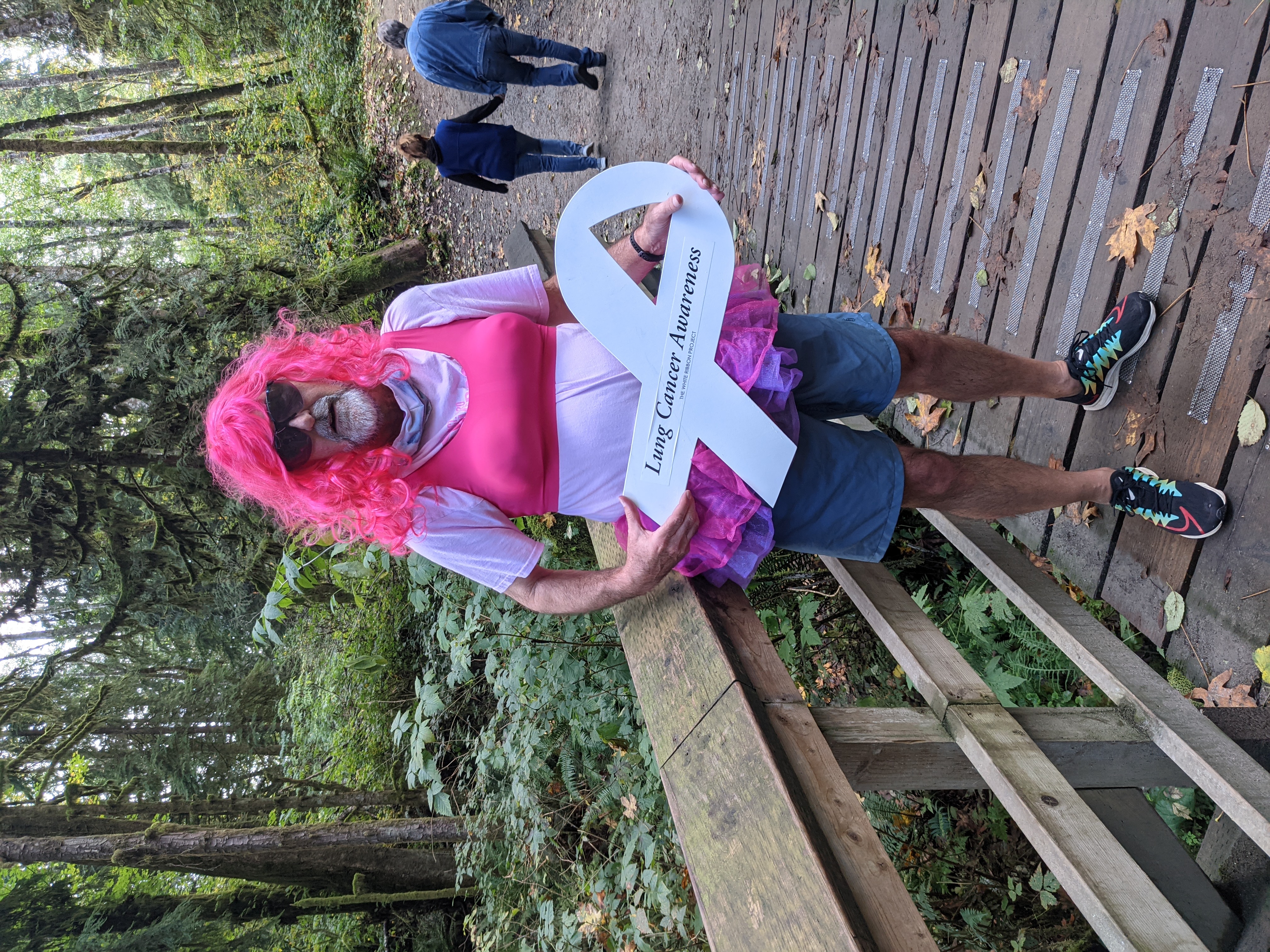 Standing on a bridge with a pink wig, pink bra and a pink tutu holding a White Ribbon for lung cancer awareness.